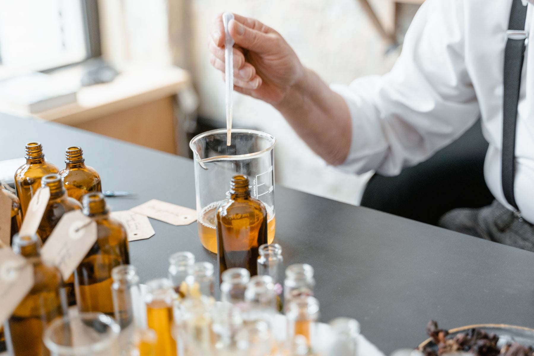 Perfumer measuring fragrance oils in a small-batch workshop